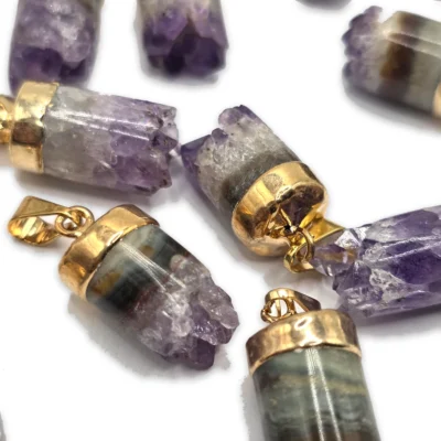 Cilindros de cuarzo vistos de cerca: franjas grises, ámbar y blancas rematadas en puntas violetas, con casquillos dorados