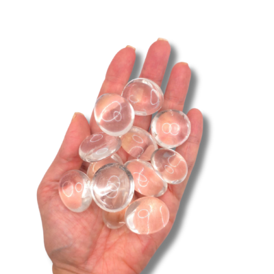 Dos rodados grandes de cuarzo incoloro, transparentes y aplanados como lentes, sostenidos en una mano.
