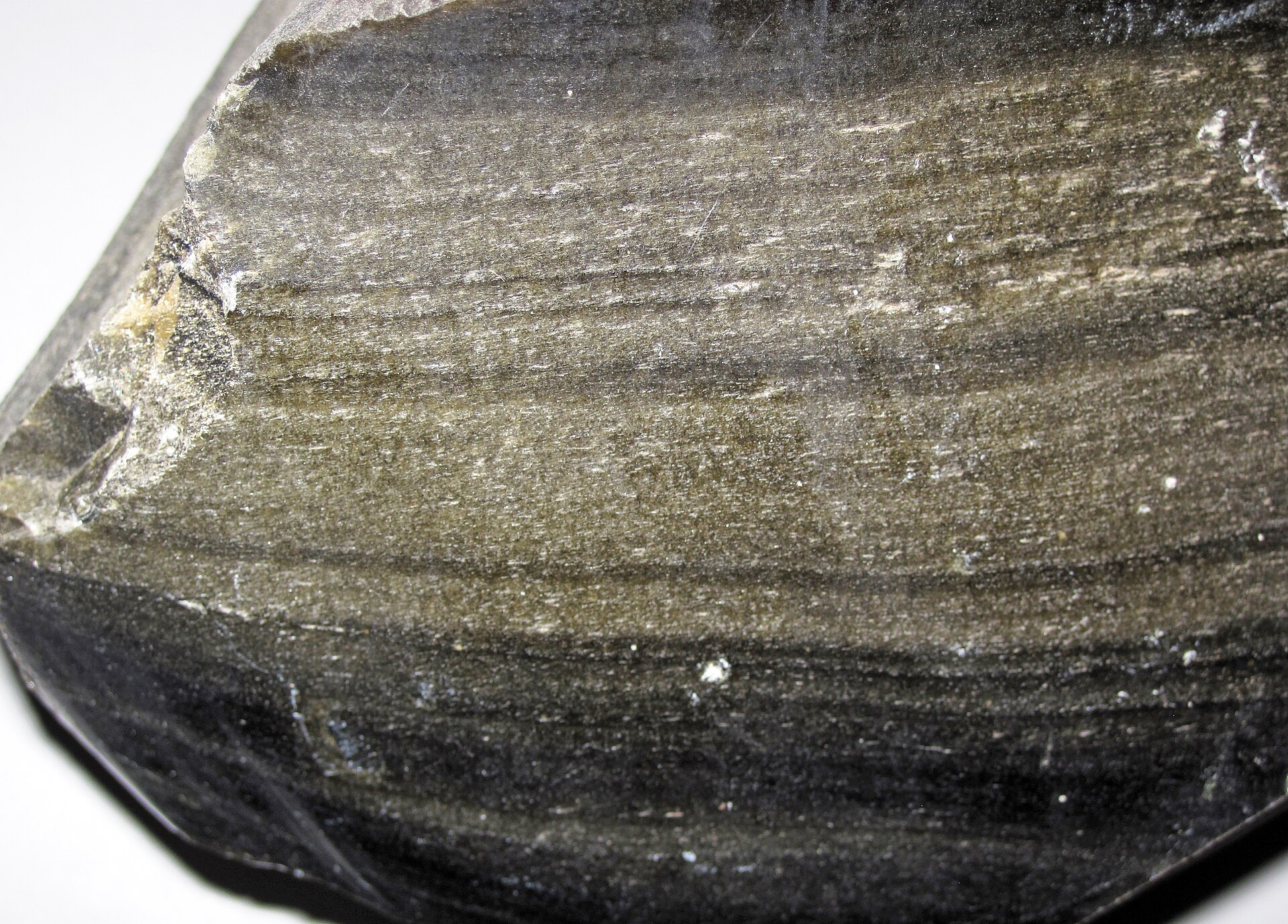 Superficie de fractura de obsidiana dorada de México, con bandas de brillo dorado