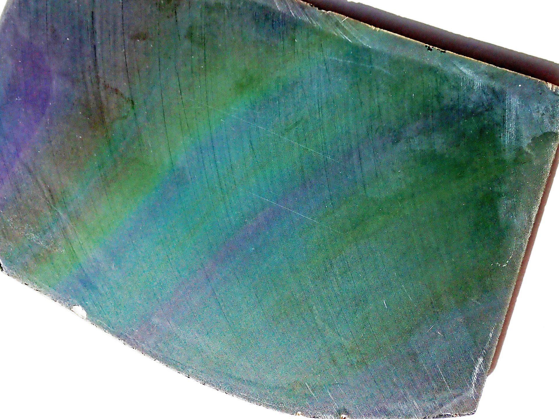 Superficie cortada de obsidiana arcoíris, con bandas verdes, azules y violetas