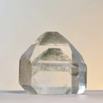 Punta de cuarzo transparente con una pirámide de polvo verde dentro, alineada bajo la punta tallada