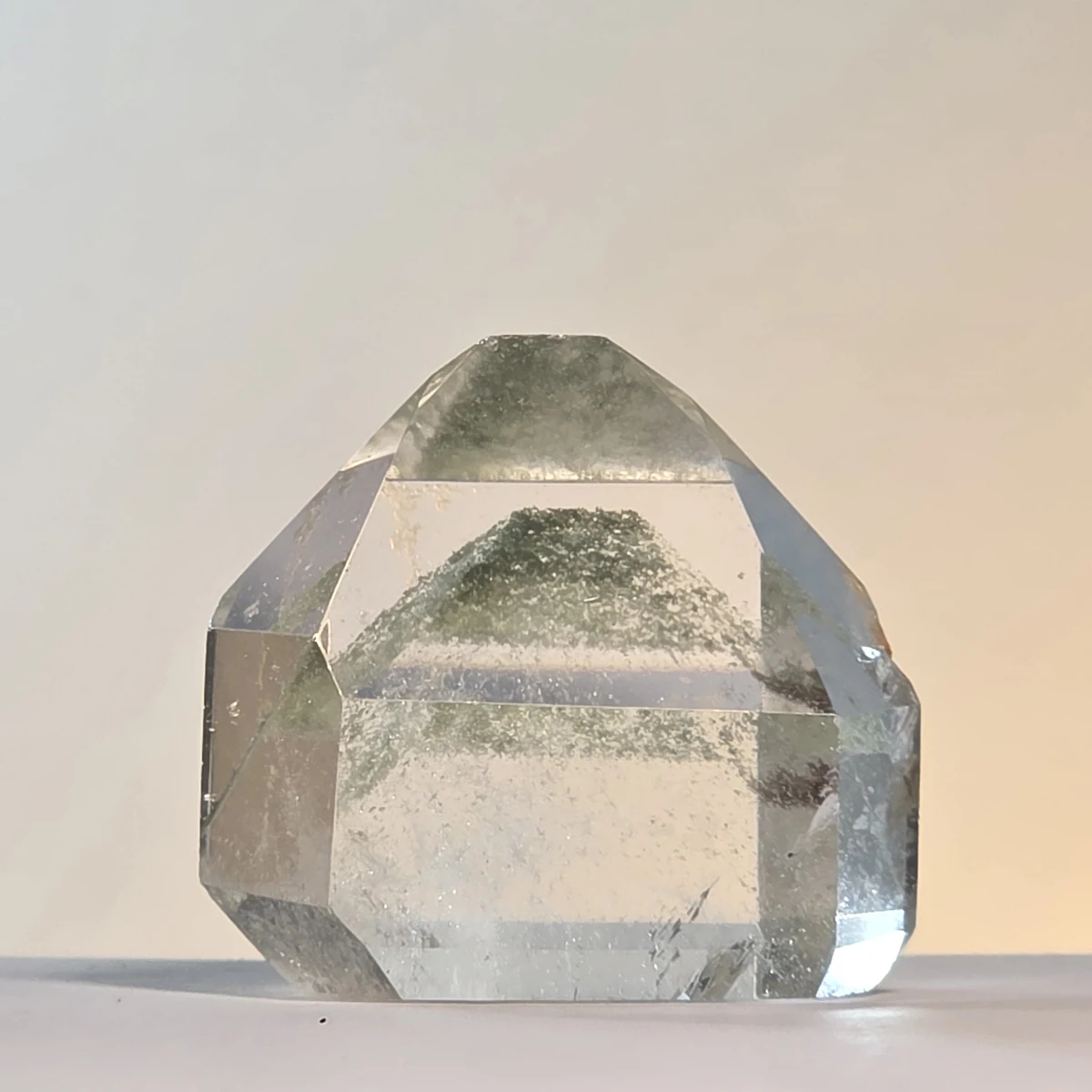 Punta de cuarzo transparente con una pirámide de polvo verde dentro, alineada bajo la punta tallada